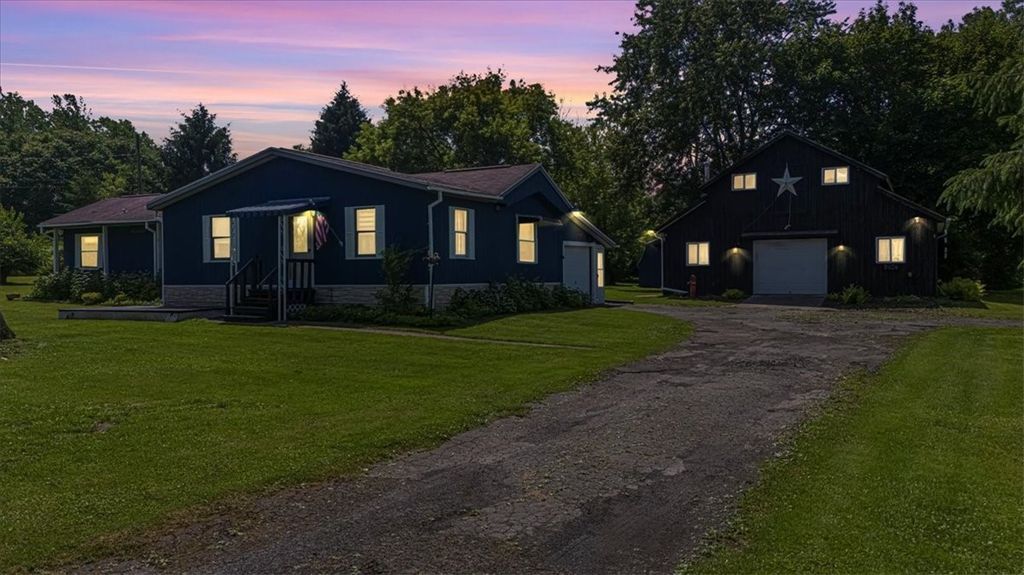A picture of a ranch style home at dusk with a large unattached garage.